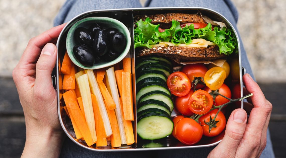 Tekst o zdrowym i smacznym jedzeniu w podróży. Na zdjęciu: Pudełko na lunch z warzywami i kanapką - HelloZdrowie