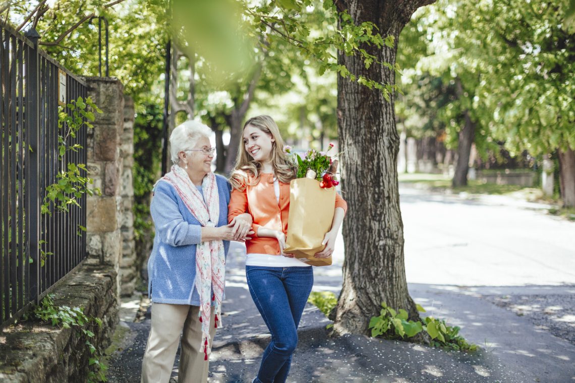 Tekst o różnych prostych sposobach pomagania innym. Na zdjęciu: Kobieta trzymająca worek z kwiatami i kobieta idąca chodnikiem - HelloZdrowie