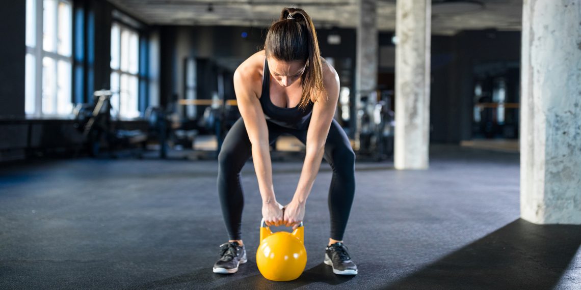 Tekst o ćwiczeniu swing z kettlebell dla każdego. Na zdjęciu: Kobieta podnosząca kettlebell - HelloZdrowie