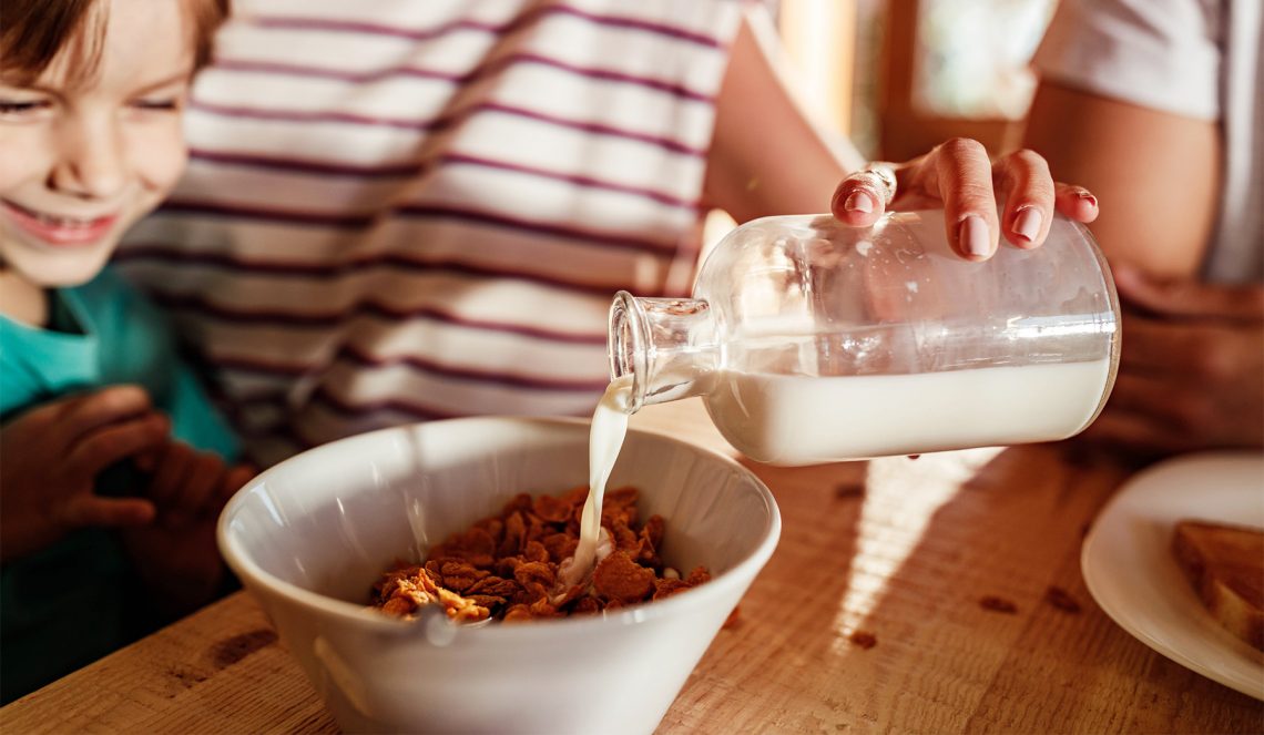 Tekst o korzyściach zdrowotnych żywności ekologicznej. Na zdjęciu: Osoba wlewająca mleko do miski z płatkami - HelloZdrowie