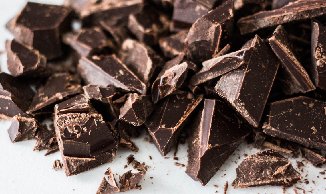 Tekst o zdrowotnych zaletach spożywania gorzkiej czekolady. Na zdjęciu: Sterta kawałków czekolady - HelloZdrowie
