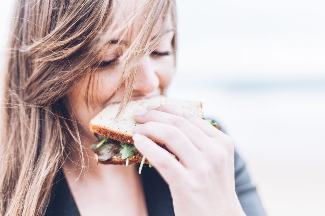 Tekst o wpływie diety na zmęczenie i energię. Na zdjęciu: Kobieta jedząca kanapkę - HelloZdrowie