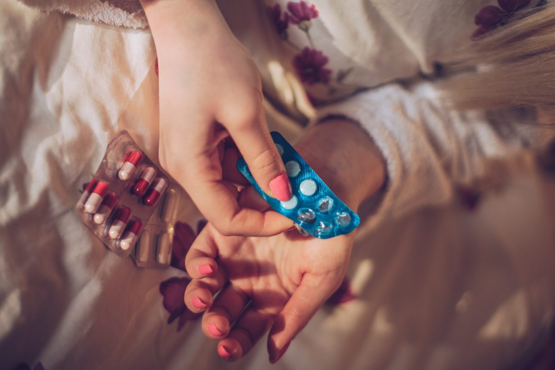 Tekst o zasadach bezpiecznego stosowania leków przeciwbólowych. Na zdjęciu: Osoba trzymająca niebieski i biały blister z tabletkami - HelloZdrowie