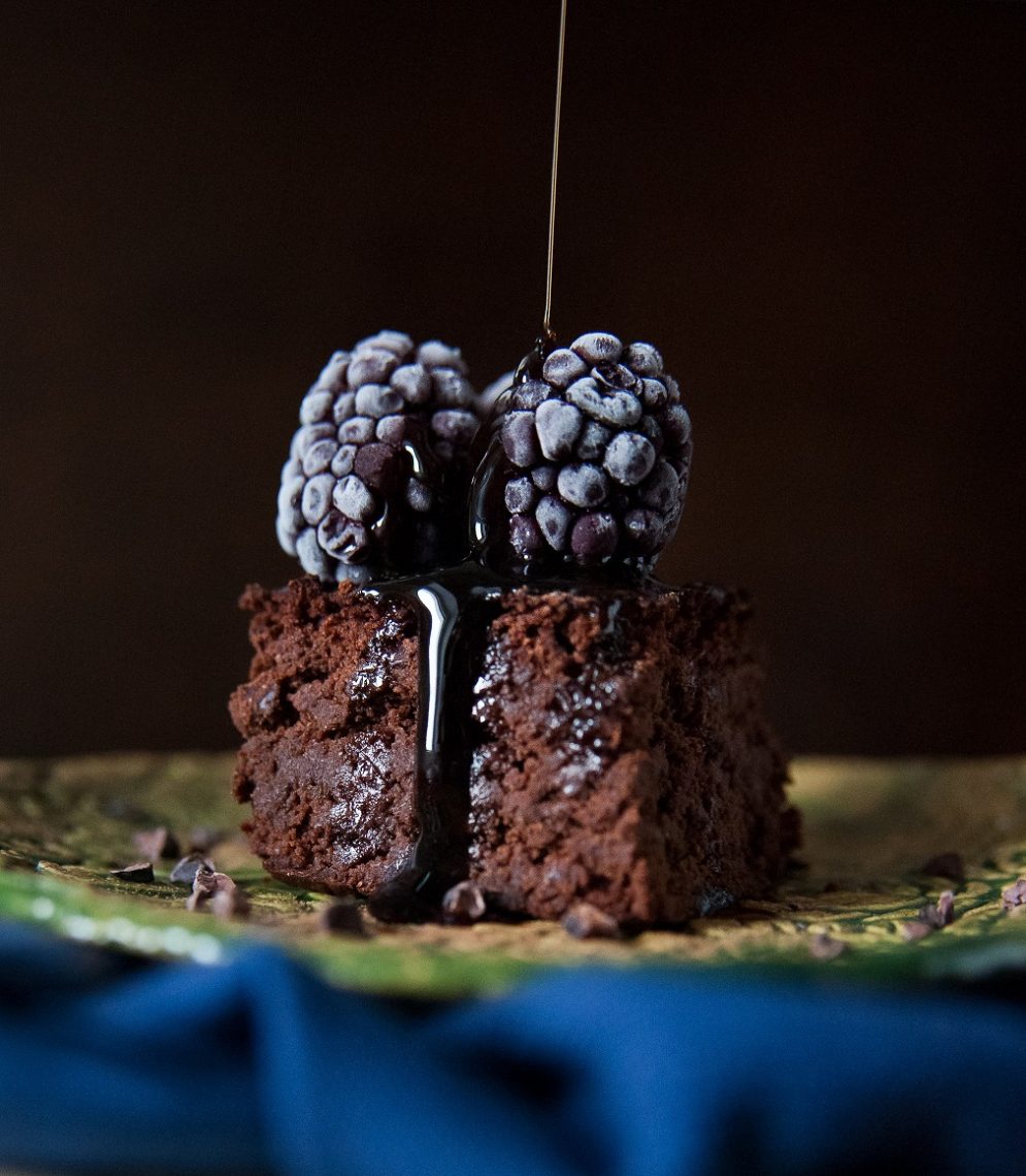 Tekst o wegańskim brownie z fasoli i jego zaletach. Na zdjęciu: Ciasto czekoladowe z owocami jagodowymi i syropem - HelloZdrowie