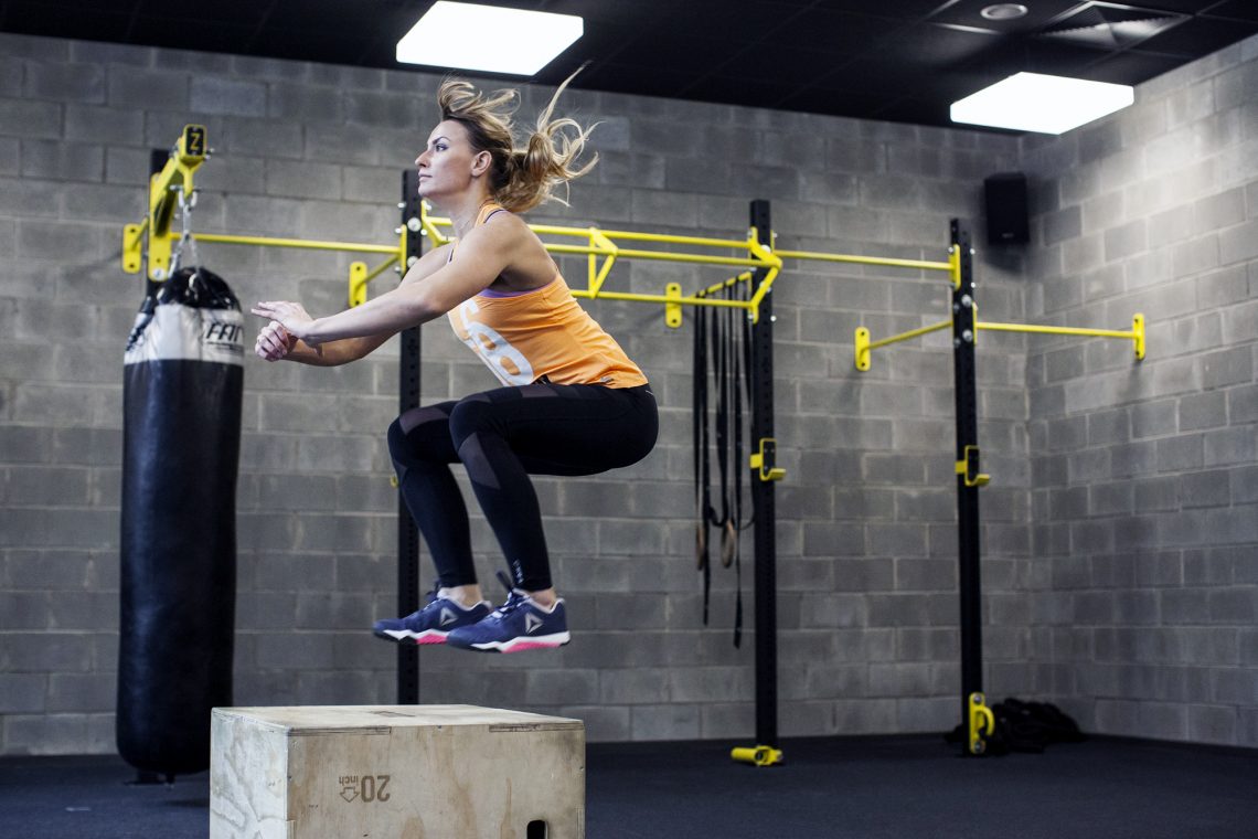 Tekst o korzyściach i technice ćwiczeń box jumps. Na zdjęciu: Kobieta skacząca na skrzynię - HelloZdrowie