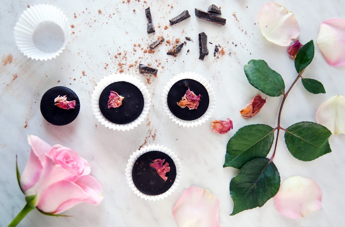 Tekst o domowych słodyczach na walentynki. Na zdjęciu: Grupa czekoladek z różowymi kwiatami i liśćmi - HelloZdrowie
