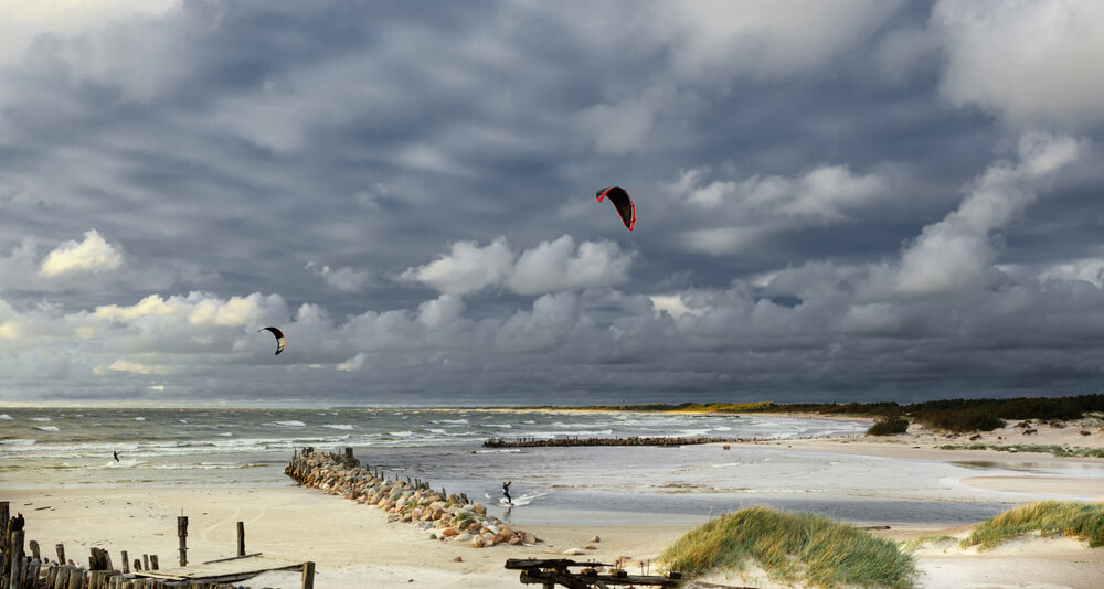 Tekst o zaletach i nauce kitesurfingu. Na zdjęciu: Grupa ludzi pływających na desce kite na plaży - HelloZdrowie