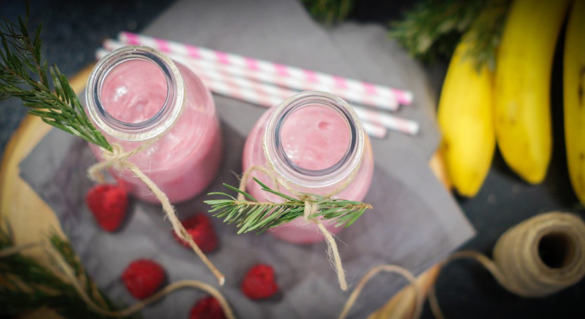 Tekst o koktajlu z malin i rozmarynu. Na zdjęciu: Dwa słoiki różowych smoothie - HelloZdrowie