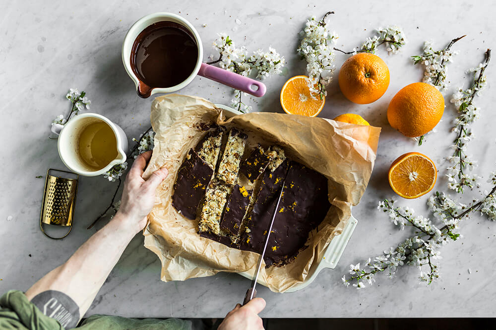 Tekst o zdrowym deserze z migdałami i czekoladą. Na zdjęciu: Osoba krojąca kawałek ciasta czekoladowego - HelloZdrowie