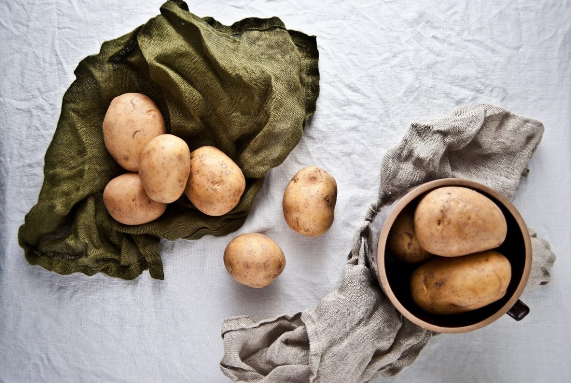 Tekst o pieczonych wegańskich plackach ziemniaczanych. Na zdjęciu: Miska z ziemniakami i miska z kawałkami materiału - HelloZdrowie