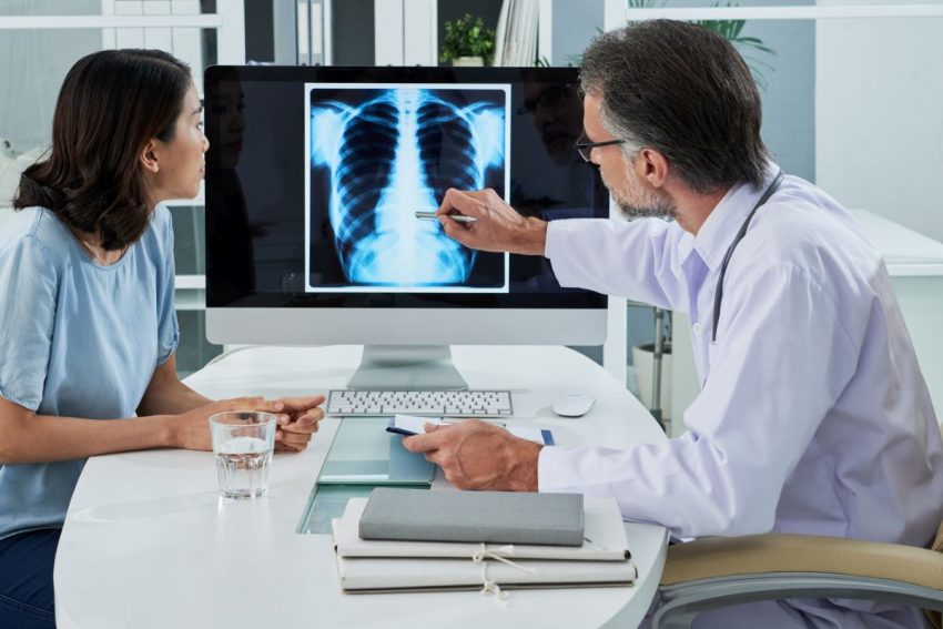 Lekarz pokazuje na rentgen i tłumaczy pacjentce przyczyny zapalenia płuc