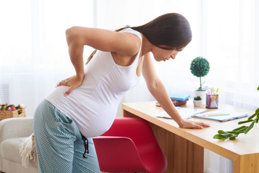Kobieta w ciąży trzymająca się za plecy z powodu bólu pleców