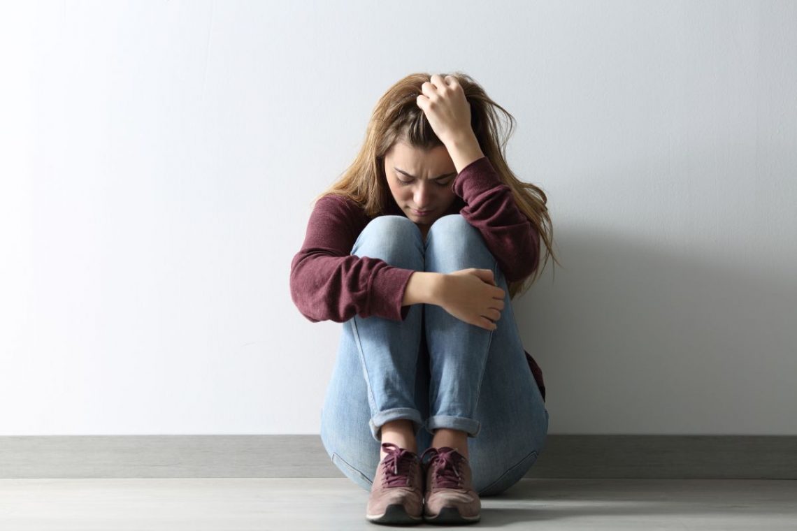Kobieta z depresją siedzi oparta o ścianę