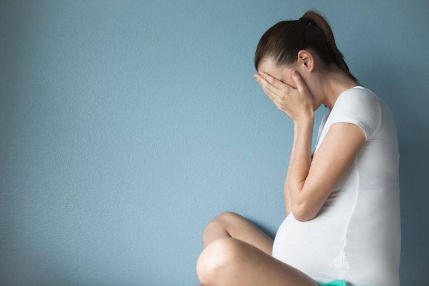 Kobieta w ciąży trzyma się za głowę z powodu depresji