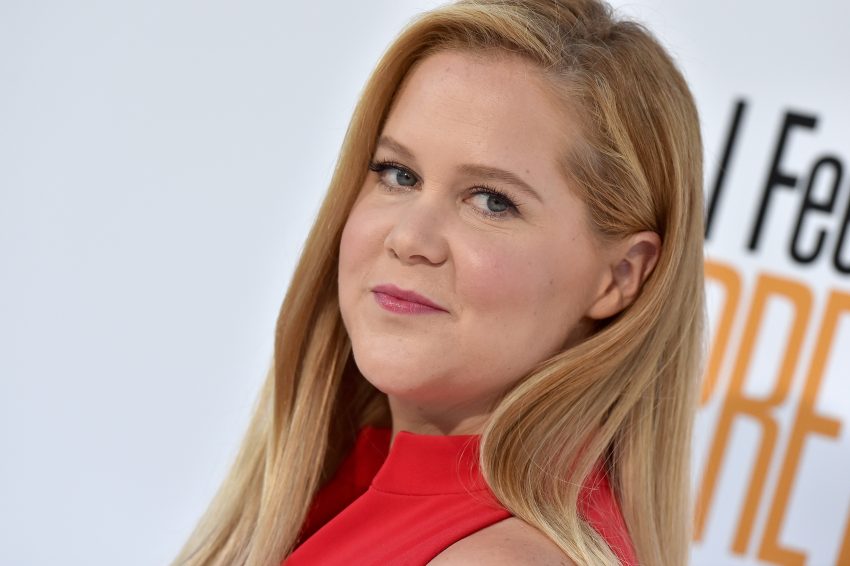 Amy Schumer w czerwonej sukience pozuje na ściance