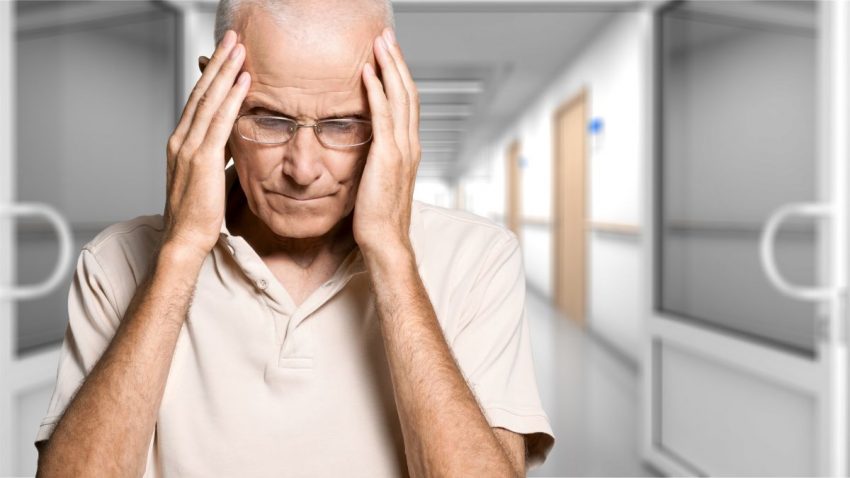 Mężczyzna trzyma się za głowę z powodu objawów udaru mózgu