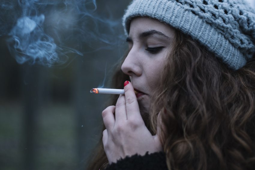 kobieta w czapce pali papierosa