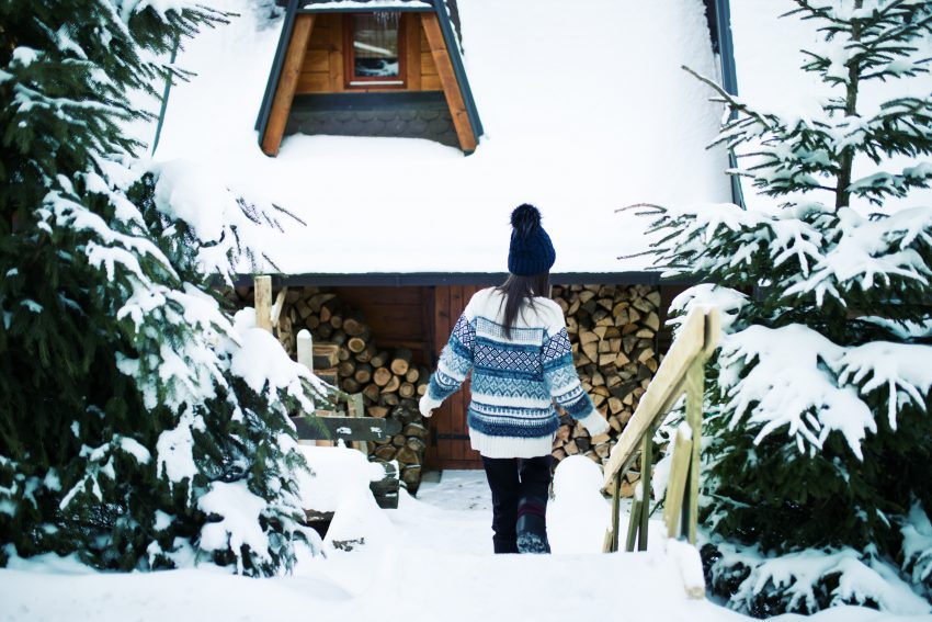 Kobieta pod drewnianą chatą zima