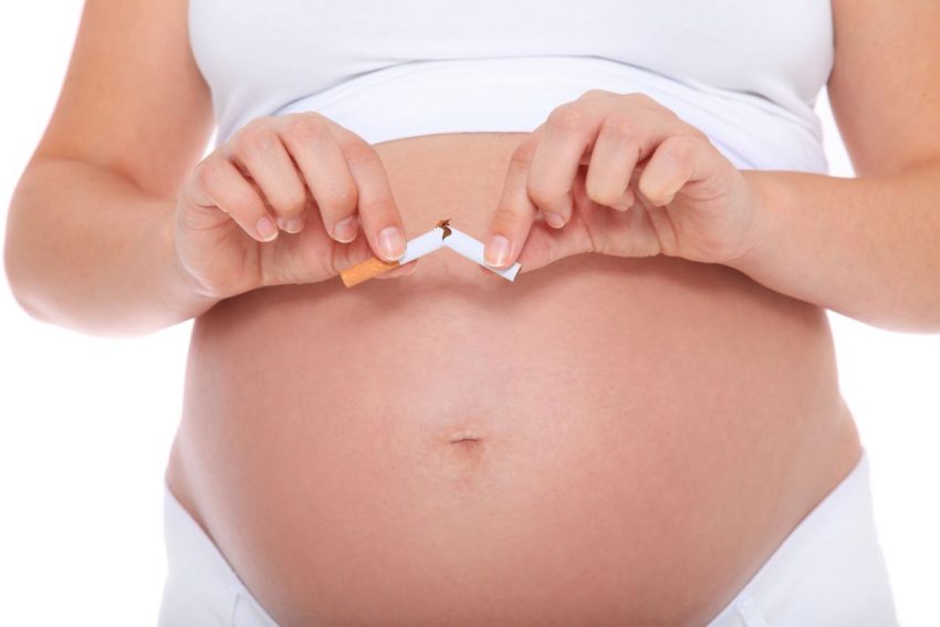 Kobieta w ciąży z odkrytym brzuchem przerywa na pół papieros.