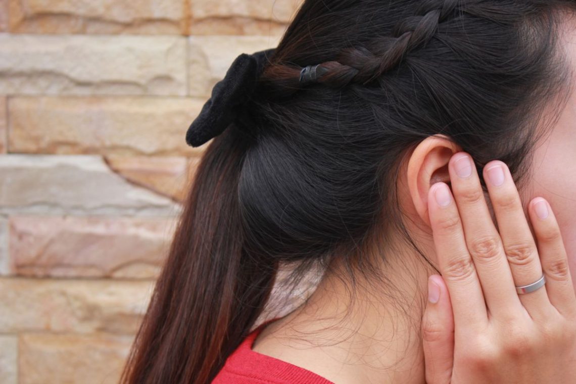 Kobieta cierpiąca na perlaka trzyma się za ucho