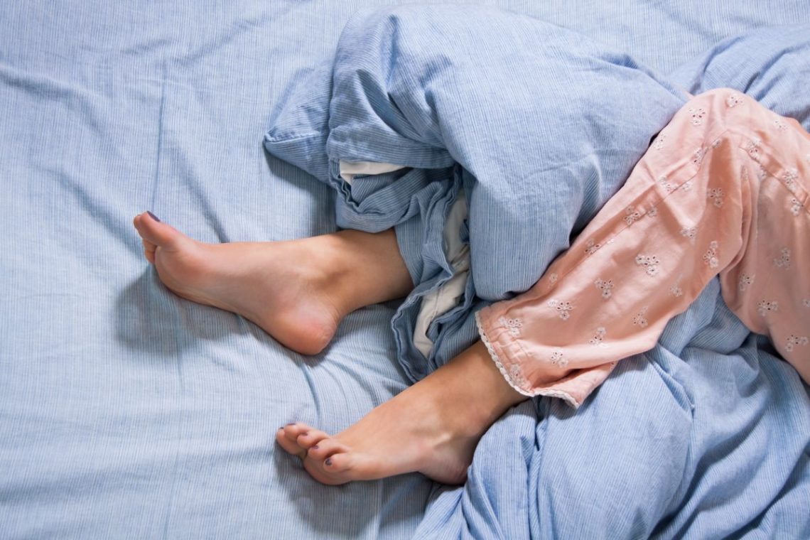 podkurczone nogi w trakcie leżenia na łóżku spowodowane zespołem niespokojnych nóg