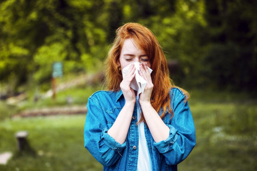 Dlaczego kichamy? Poznaj mniej i bardziej znane przyczyny kichania; na zdjęciu kichająca kobieta- Hello Zdrowie