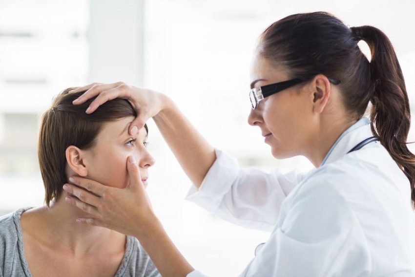 Lekarka w okularach robi badanie okulistyczne pacjentce w krótkich włosach