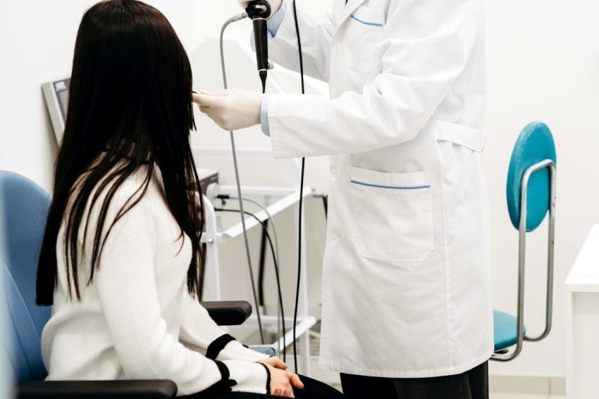 lekarz przeprowadza kobiecie badanie gardła fiberoskopem