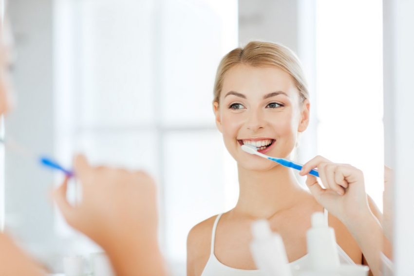 młoda kobieta w łazience myje zęby szczoteczką