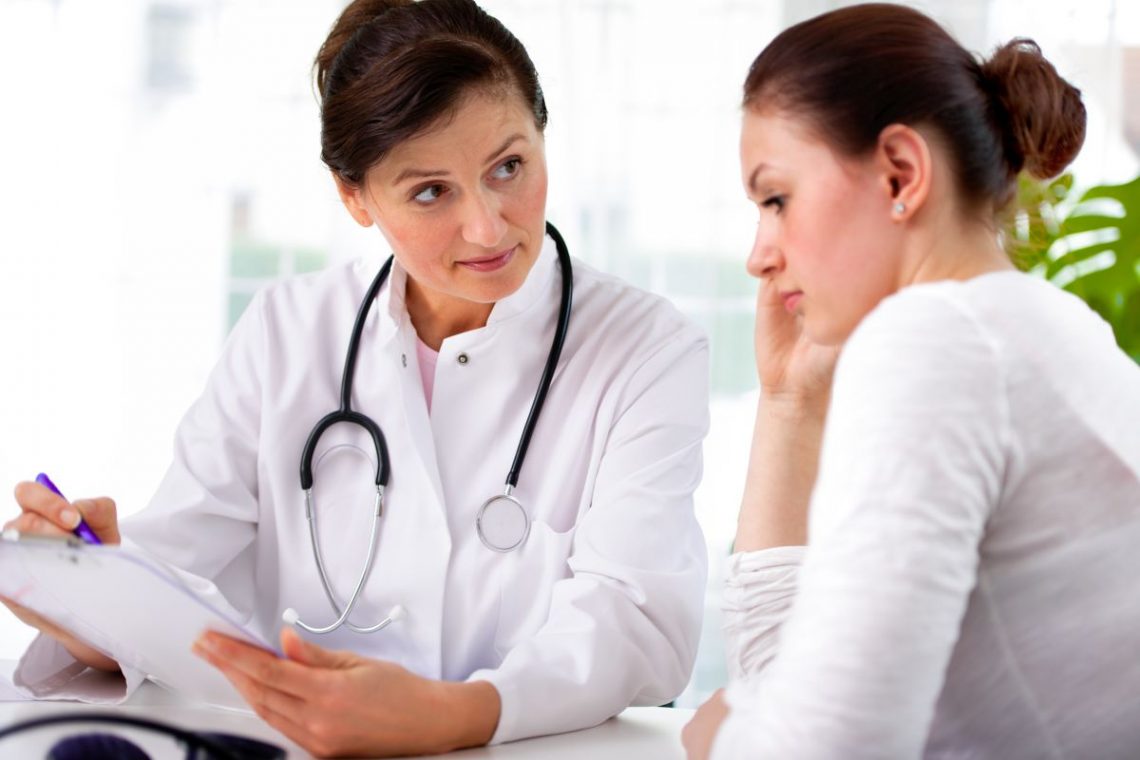 Kobieta zmartwiona siedzi u lekarza i słucha, co mówi do niej lekarka