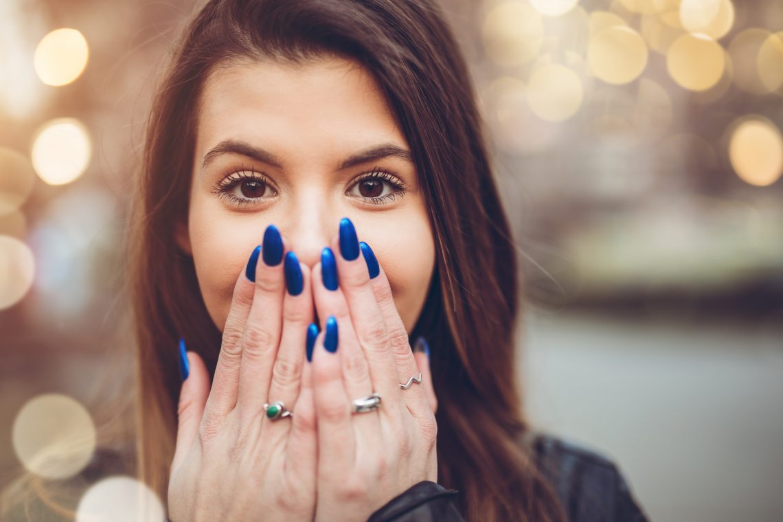młoda kobieta zakrywa usta dłońmi