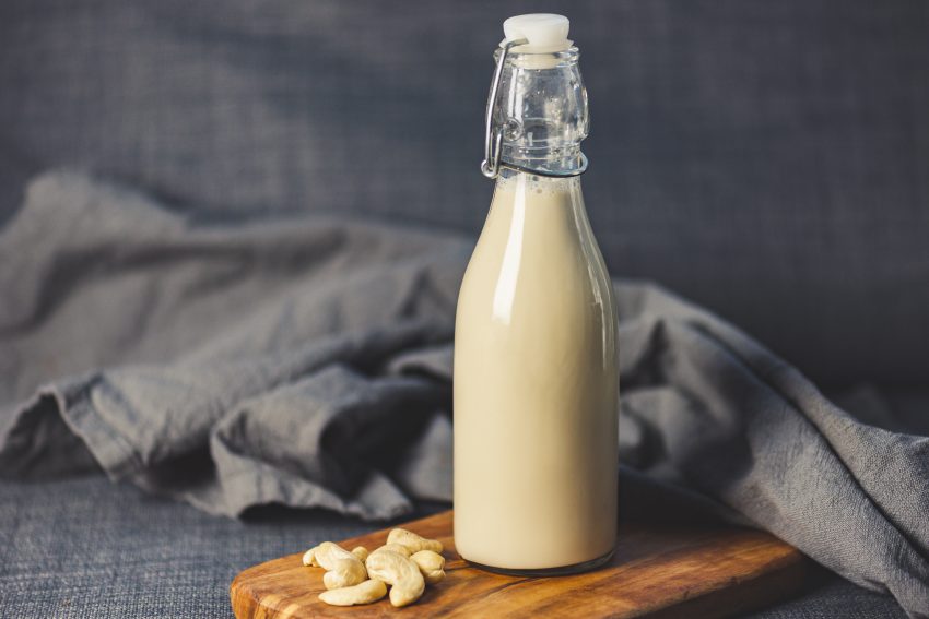 Tekst o domowej produkcji mleka roślinnego. Na zdjęciu: Butelka mleka na desce drewnianej - HelloZdrowie