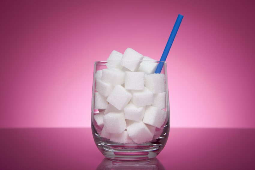 Tekst o nadmiernym spożyciu cukru i otyłości Polaków. Na zdjęciu: Szklanka pełna kostek cukru - HelloZdrowie