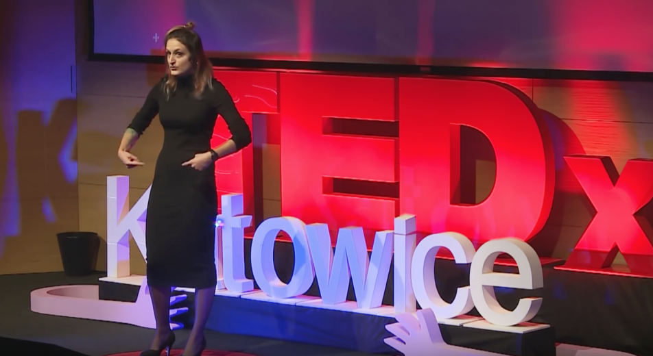 młoda kobieta w czarnych ciuchach stoi na scenie podczas konferencji tedx