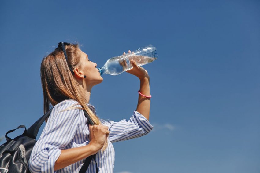 odwodnienie organizmu - kobieta pije wodę z butelki