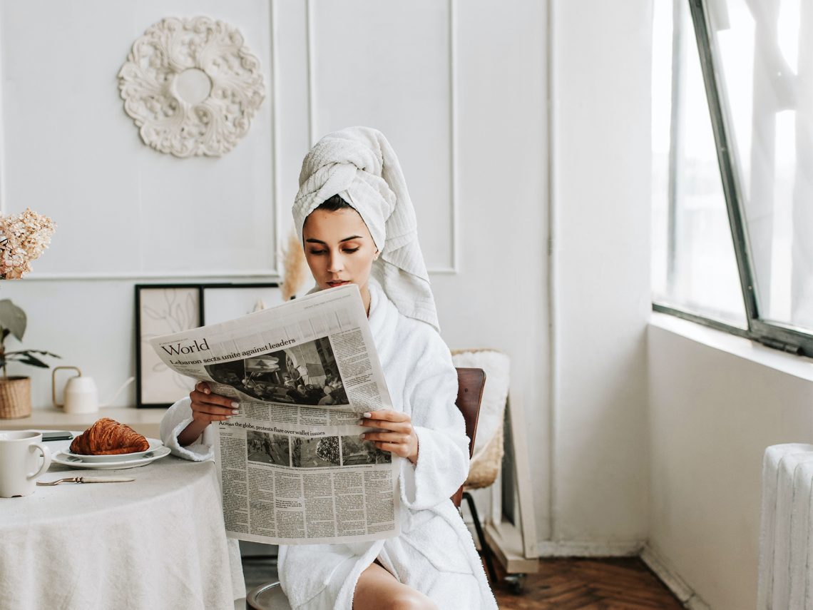 Kobieta czyta gazetę przy śniadaniu
