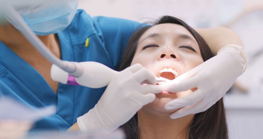 dentysta czyści kobiecie zęby specjalnym przyrządem