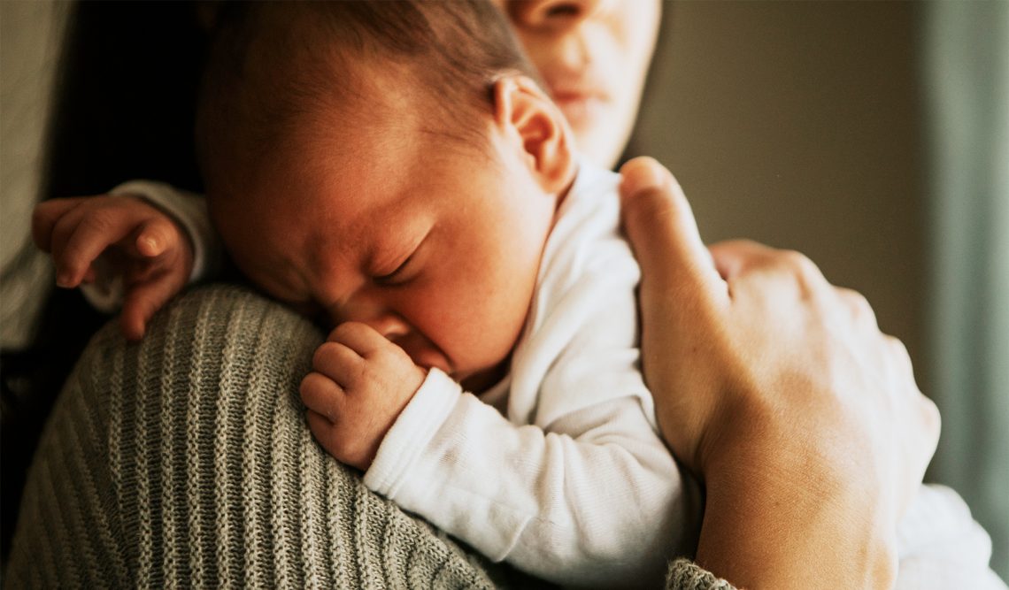 Kobieta trzyma na rękach dziecko, które ma kręcz szyjny