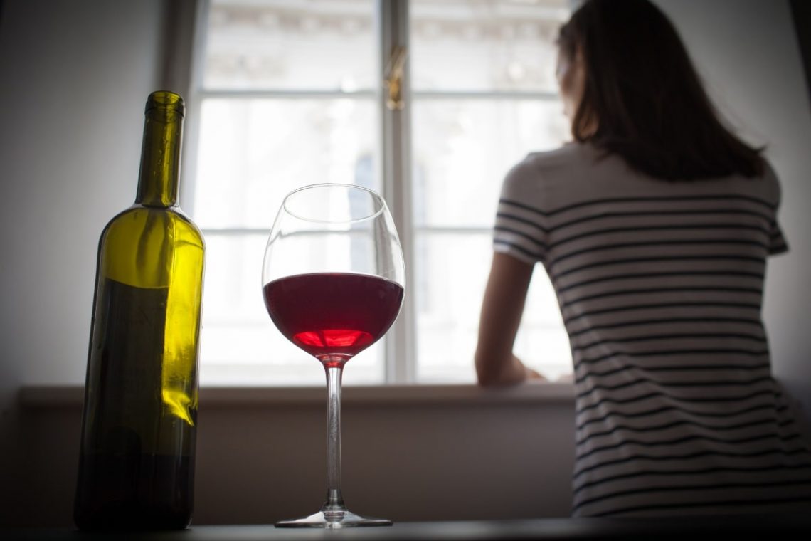 Lampka wina i kobieta patrząca się przez okno