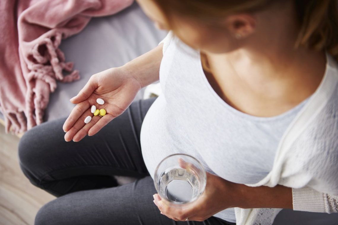 Kobieta w ciąży łyka tabletki