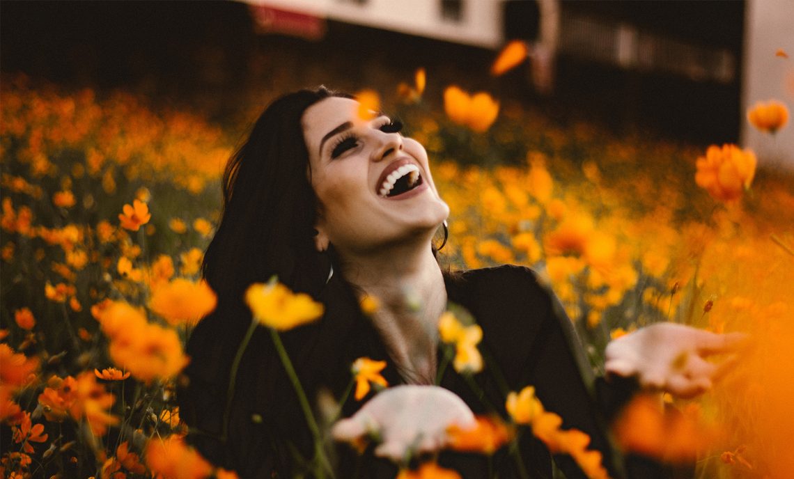 Tekst o procedurze bondingu zębów, efektach i trwałości. Na zdjęciu: Kobieta na polu kwiatów - HelloZdrowie