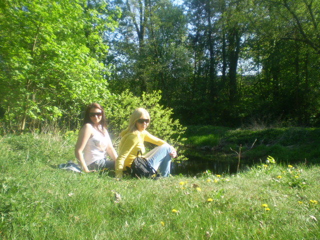 Tekst o przyjaźni dwóch różnych kobiet od ćwierćwiecza. Na zdjęciu: Dwie kobiety siedzące na trawie obok strumienia - HelloZdrowie