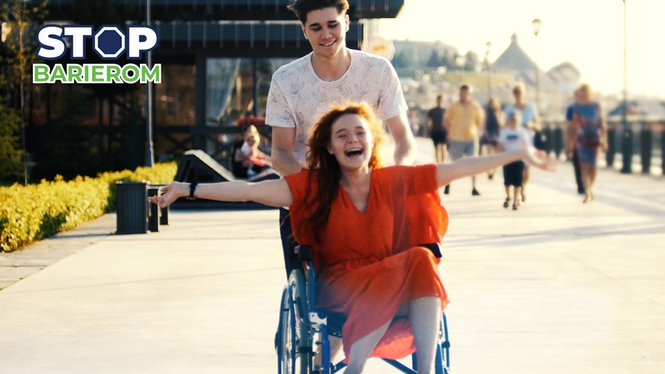 Tekst o kampanii wspierającej osoby niepełnosprawne. Na zdjęciu: Mężczyzna pchający kobietę na wózku inwalidzkim - HelloZdrowie