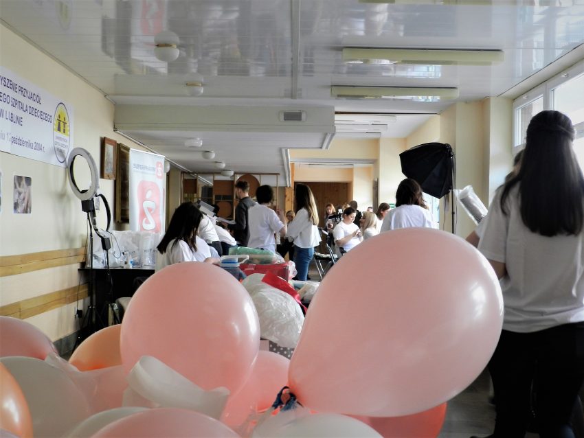 Tekst o wsparciu mam chorych dzieci w szpitalach. Na zdjęciu: Grupa ludzi w korytarzu z balonami - HelloZdrowie