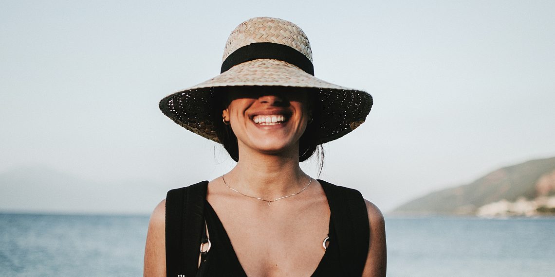 Tekst o łagodzeniu objawów alergii w sezonie pylenia. Na zdjęciu: Kobieta nosząca kapelusz i uśmiechając się - HelloZdrowie