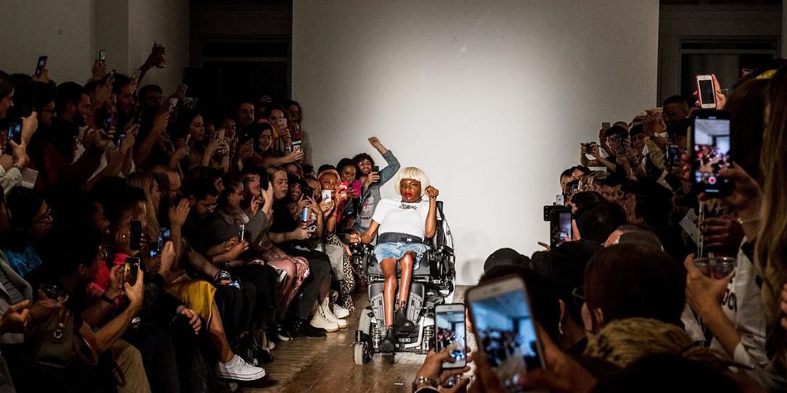 Tekst o przełomowym pokazie transpłciowej modelki Aaron Philip. Na zdjęciu: Kobieta na wózku inwalidzkim z tłumem ludzi - HelloZdrowie