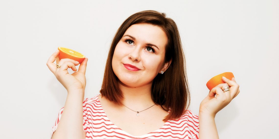 Tekst o insulinooporności i jej dietetycznych aspektach. Na zdjęciu: Kobieta trzymająca pomarańcze i uśmiechająca się - HelloZdrowie