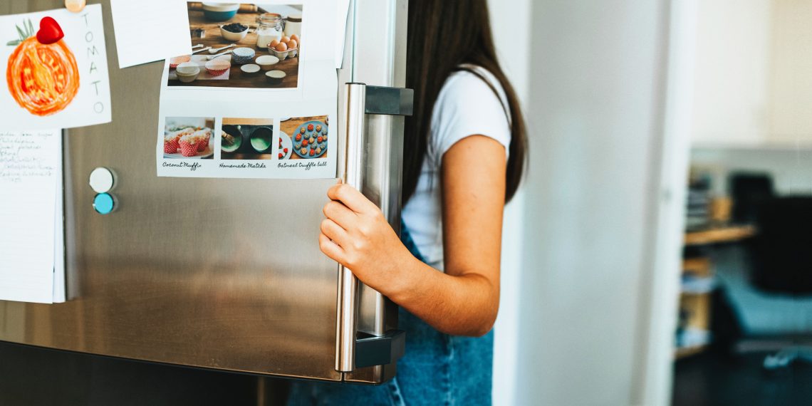 Tekst o powszechnych mitach kuchennych i ich obaleniu. Na zdjęciu: Kobieta trzymająca lodówkę - HelloZdrowie