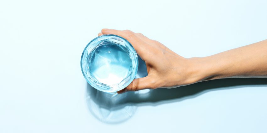 Dłoń oparta o szklankę wody
