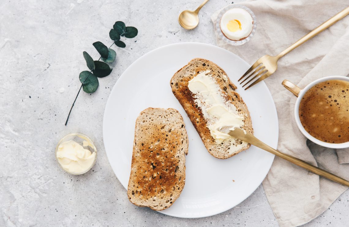 Tekst o zdrowotnych aspektach spożywania masła. Na zdjęciu: Talerz z tostami z masłem - HelloZdrowie